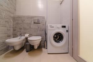 a bathroom with a toilet sink and a washing machine at Casa Anastasia with private patio by GardaDoma in Brenzone sul Garda +3 photos