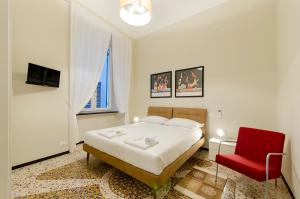 ein Schlafzimmer mit einem Bett und einem roten Stuhl in der Unterkunft JOIVY The Place To Be in the Centre of Genoa in Genua