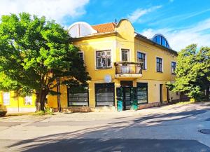 a yellow building with a tree in front of it at Bástya Apartman in Tata