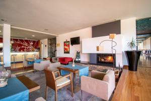 a living room with a fireplace and tables and chairs at Hotel Santa Margarida in Oleiros