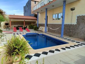 una piscina frente a una casa con sillas rojas en Casa Miami, en Tarrafal