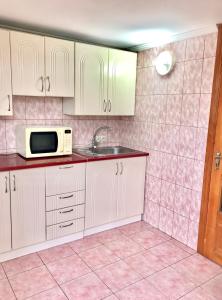 eine Küche mit weißen Schränken, einer Spüle und einer Mikrowelle in der Unterkunft Квартира in Czernowitz