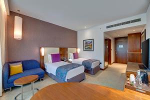 una camera d'albergo con due letti e un divano di Crowne Plaza Muscat OCEC, an IHG Hotel a Mascate