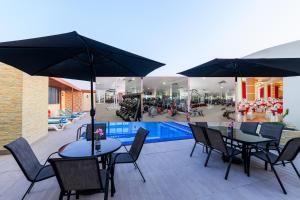 a patio with tables and umbrellas and a swimming pool at Plaza Inn Doha in Doha