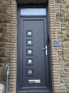 a black door in a brick building with a brick wall at Neat Retreat-Cilfynyd-Pontypridd in Pontypridd