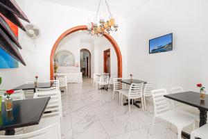 a dining room with white chairs and tables and a chandelier at Phase Guesthouse in Xewkija