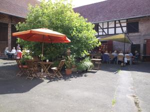 een patio met tafels en stoelen en een parasol bij Rhönhof Lebensart in Friedewald