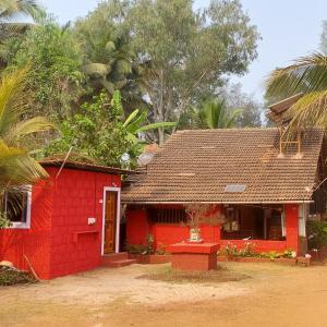 a red house with a red door and trees at Samarth Atc-Beach Home Stay in Ratnagiri