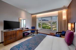 Habitación de hotel con cama, escritorio y TV. en Crowne Plaza Muscat OCEC, an IHG Hotel en Mascate