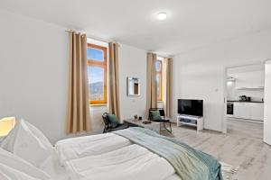 a white bedroom with a bed and a kitchen at FarawayHomes Studio Sankt Michael #10 in Sankt Michael in Obersteiermark