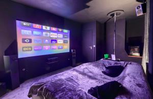 een kamer met een bed met een groot scherm bij 50 Nuances d'Amour - Jacuzzi / Massage / Cinéma in Moirans