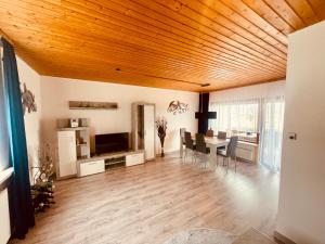 a living room with a wooden ceiling and a dining room at 1 - Gemütlicher Bungalow am Fuße der Wasserkuppe in Dipperz