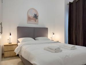 a bedroom with a large white bed with towels on it at Glenvar Heights I1 90 sqm apt in Paleo Faliro in Athens