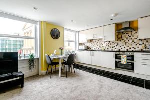 una cocina con armarios blancos y una mesa con sillas. en Brighton Lanes Cosy One Bedroom Apartment, en Brighton & Hove