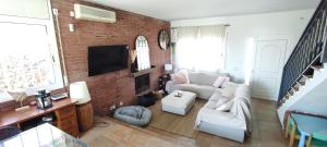 sala de estar con muebles blancos y pared de ladrillo en Villa Brisas - Preciosa villa con gran intimidad y piscina, en Segur de Calafell