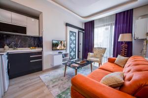 a living room with an orange couch and a kitchen at SEYİREVLERİ SUİT ŞUBESİ in Melikgazi