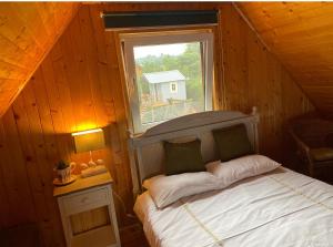 a bedroom with a bed and a window in a cabin at Domek Lawendowe Zacisze in Odargowo