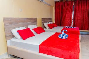 1 Schlafzimmer mit 2 Betten mit roten und blauen Kissen in der Unterkunft Casa bella Beach apartment in Ukunda
