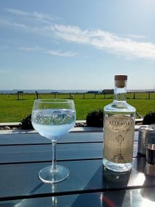 a bottle of gin and a glass of water on a table at Flotnar Hús - Ensuite Rooms in Keiss