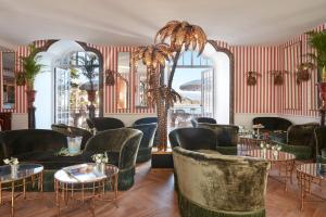a restaurant with green chairs and tables and a red striped wall at Château de Théoule Hôtel & Spa in Théoule-sur-Mer