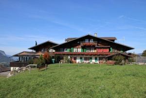 a large house sitting on top of a lush green field at Bergblick Lodge - 3 Sterne Garni - Neueröffnung in Aeschi
