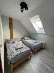 2 Betten in einem Dachzimmer mit Fenster in der Unterkunft Domki na Maciejce Domek 15 osobowy i 7 osobowy in Jaworzynka
