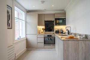 a kitchen with white cabinets and a large window at Apartment 8 - Bootham House in York