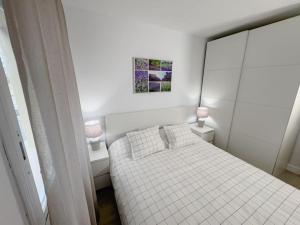 een witte slaapkamer met een wit bed en 2 lampen bij Apartamento Marina Roses in Roses