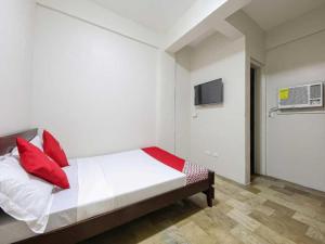 um quarto com uma cama com almofadas vermelhas e uma televisão em OYO 1069 Cittatel Inn em Manilla