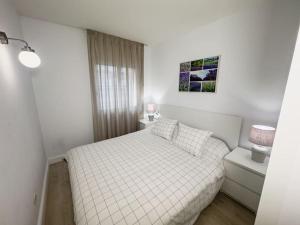 een witte slaapkamer met een bed en een raam bij Apartamento Marina Roses in Roses