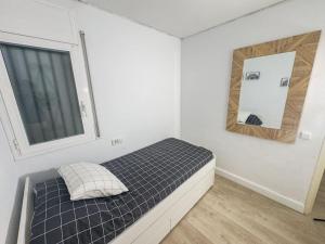 een kleine slaapkamer met een bed en een spiegel bij Apartamento Marina Roses in Roses