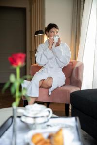 Una donna seduta su una sedia che beve una tazza di caffè di InterContinental Rome Ambasciatori Palace, an IHG Hotel a Roma