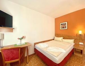Habitación pequeña con cama y escritorio. en Hotel Gasthof Rose en Günzburg