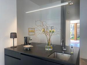 a black counter with a vase with flowers in it at Zehuus Gartenstudio mit Terrasse in Cologne +26 photos