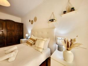 a bedroom with a white bed with a vase on a table at Amélia Apartment - Peniche Surf Camp in Peniche