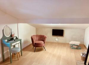 Habitación con silla, escritorio y TV. en Les Fougères 12 personnes SPA/SAUNA en Le Tholy