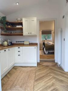 a kitchen with white cabinets and a room with a bed at Stylish 1 bed studio hot tub &gym close to Lyme in Axminster