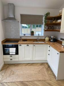 a kitchen with white cabinets and a stove top oven at Stylish 1 bed studio hot tub &gym close to Lyme in Axminster