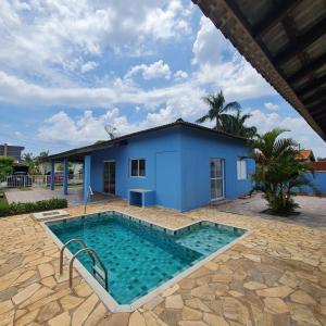 uma piscina em frente a uma casa azul em Casa em condomínio Ninho Verde 1 em Porangaba