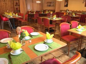 un comedor con mesas de madera y sillas rojas en Hotel Gasthof Rose en Günzburg