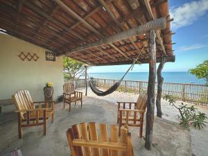 a porch with chairs and a hammock on the beach at Pousada Vila Matury in Icapuí