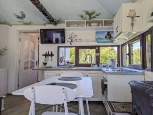 uma cozinha com armários brancos e uma mesa e cadeiras em Theea's tiny house em Certeju de Sus