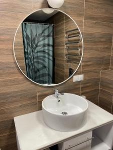 La salle de bains est pourvue d'un lavabo blanc et d'un miroir. dans l'établissement Cozy Urban Retreat, à Panevėžys