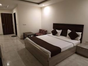 a bedroom with a large bed and a chair at Hotel Samara Kingdom Near Delhi Airport in New Delhi