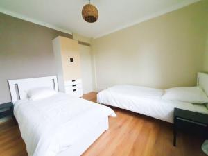 two white beds in a room with wooden floors at EXIGEHOME - Magnifique T3 à 10 km de Paris Porte de St Cloud in Vaucresson