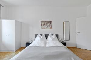 a white bedroom with a large bed with white pillows at StayEasy Apartments Krieglach W1 