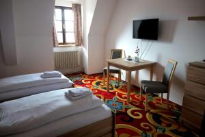 a room with two beds and a table and a television at Zámecký Penzion in Valašské Meziříčí