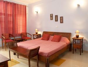 1 dormitorio con 1 cama con 2 sillas y 1 mesa en Ayurveda Bhavan, en Rishīkesh