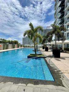 a large swimming pool with palm trees in a building at Mactan Newtown Beach Condo in Mactan