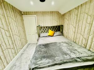 a bedroom with a bed with a yellow pillow on it at Meadow View Haven in Theydon Bois